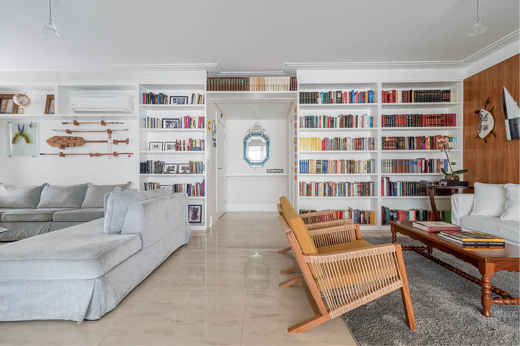 Foto de apartamento com estante cheia de livros, sofás e poltronas
