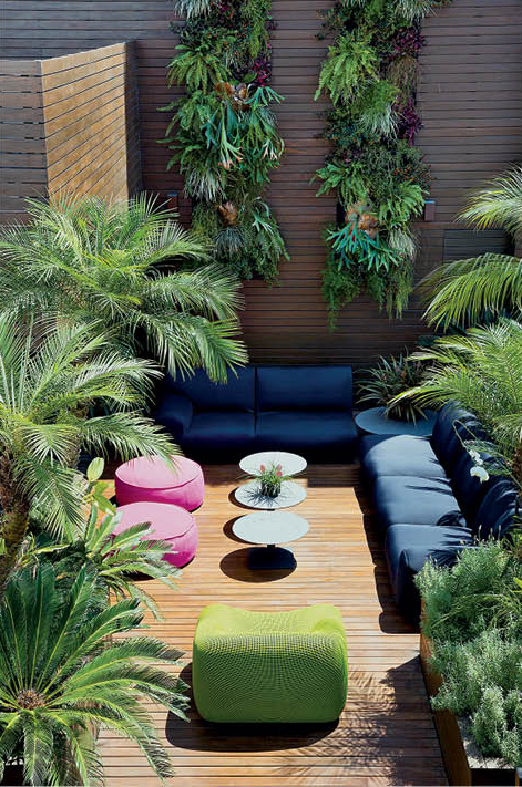 Área externa da cobertura de um apartamento dúplex com um deck de madeira e muitas plantas