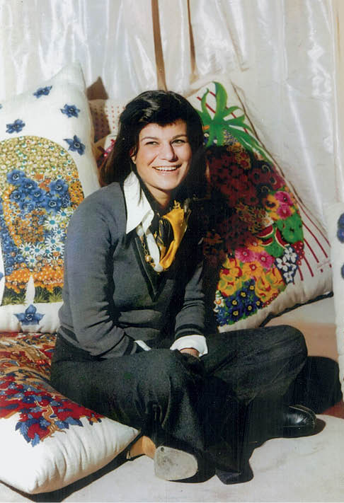 Fulvia Ferragamo sentada à frente de almofadas com estampas coloridas