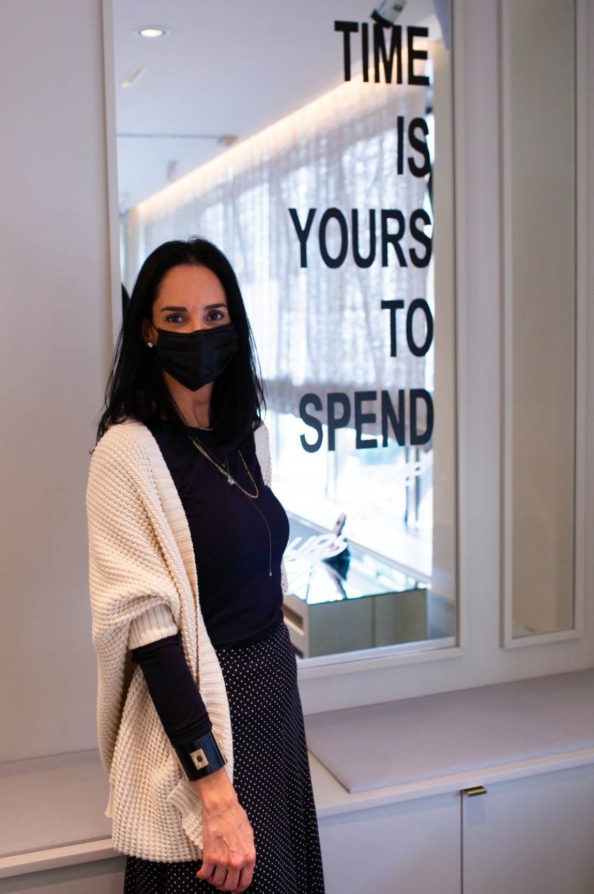 Fernanda Naman à frente de sua obra com a frase em inglês "Times is your to spend", que pode ser traduzida como "O Tempo é seu para passar"