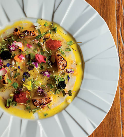 O carpaccio de camarão acompanhado por ovas de capelin, vieiras e flores dá as boas-vindas ao menu degustação tradizione do Picchi